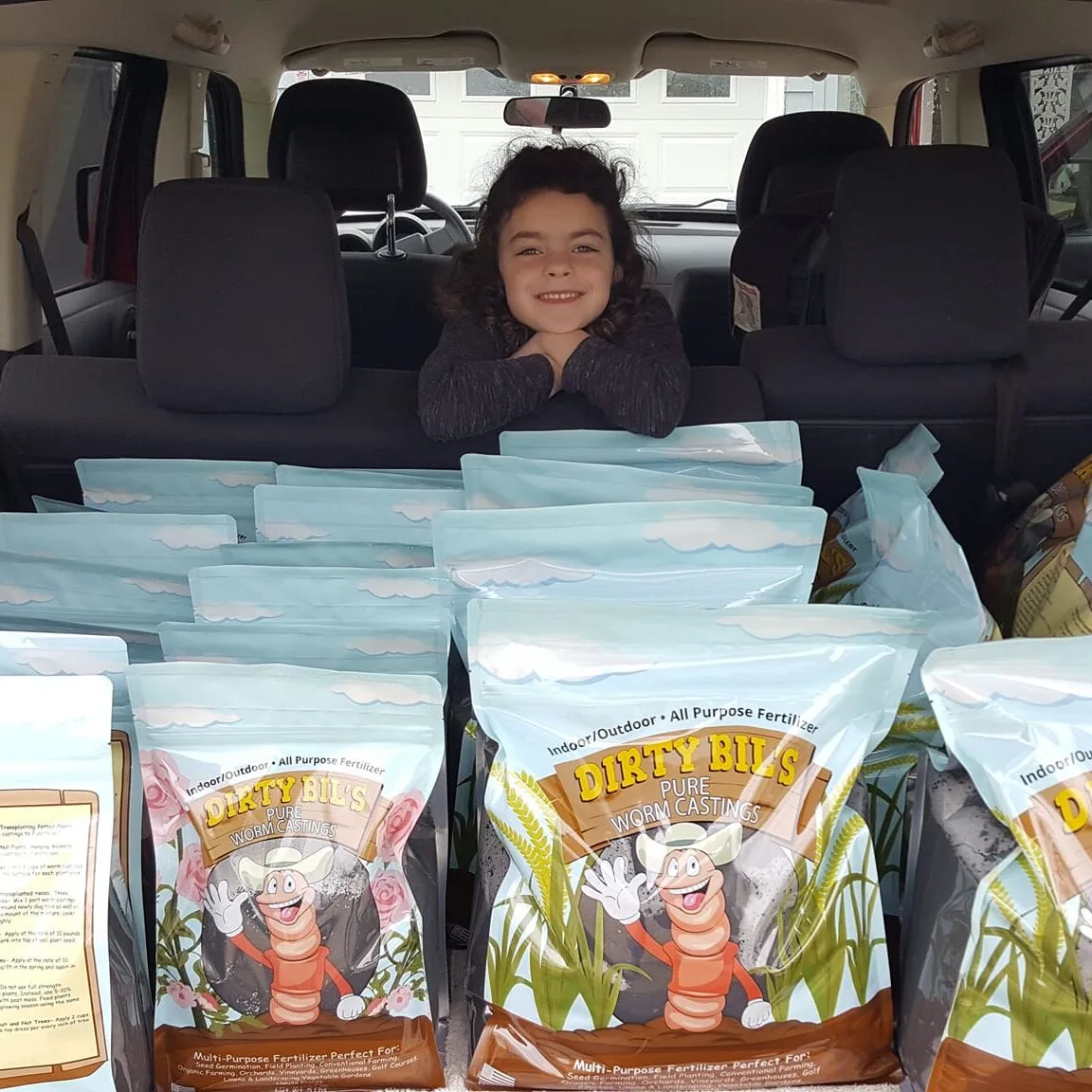 Photo of Derek Bilski's Daughter in the back of a car full of dirty bil's worm casting bagged products.